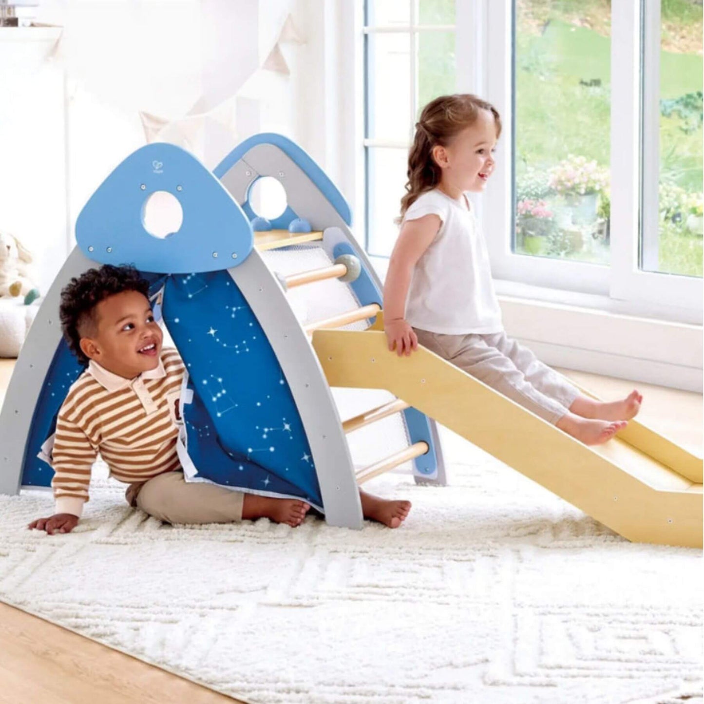 Two children playing on Hape 4-in-1 Climb 'n' Slide Gym Set in a bright room.