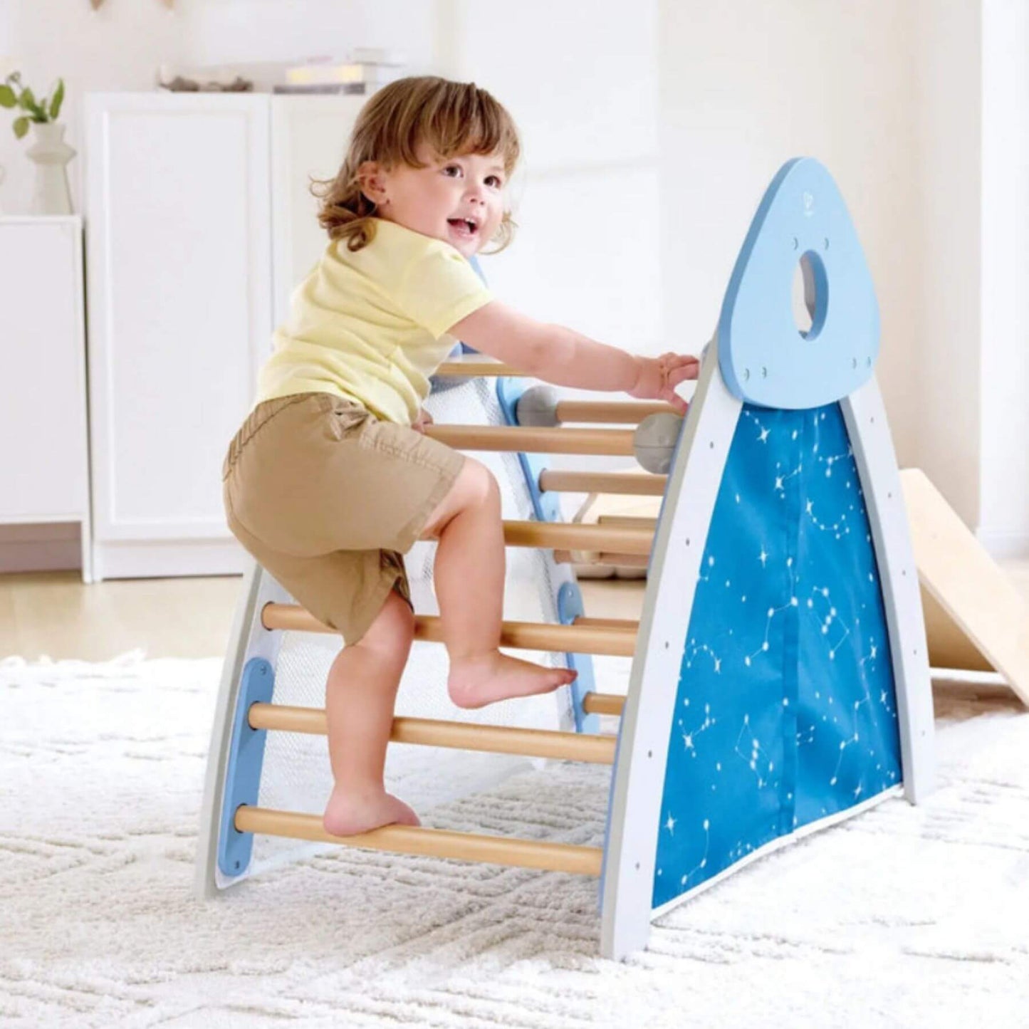 Child playing on Hape 4-in-1 Climb 'n' Slide Gym Set in a home setting