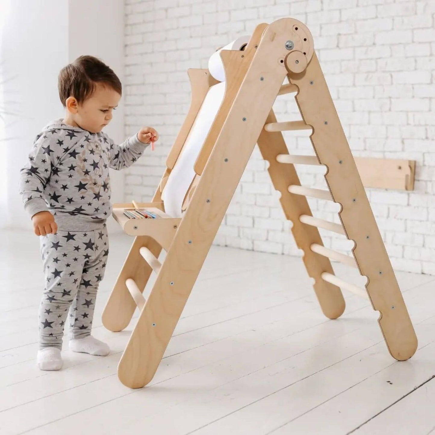 Child playing with Goodevas wooden climbing toy in a bright room.
