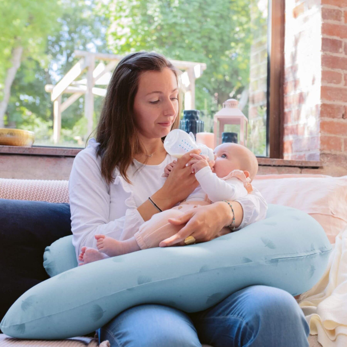 Woman holding a baby with B.Love U-Shape Pregnancy Pillow - Blue in a home setting