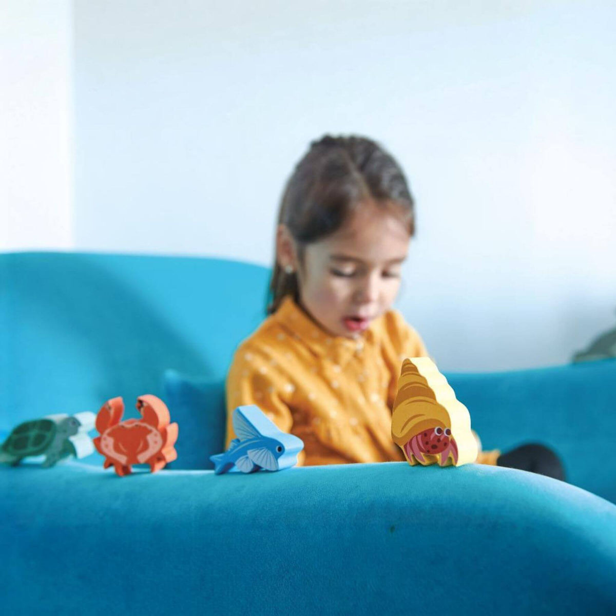Child playing with toy sea creatures on a blue couch