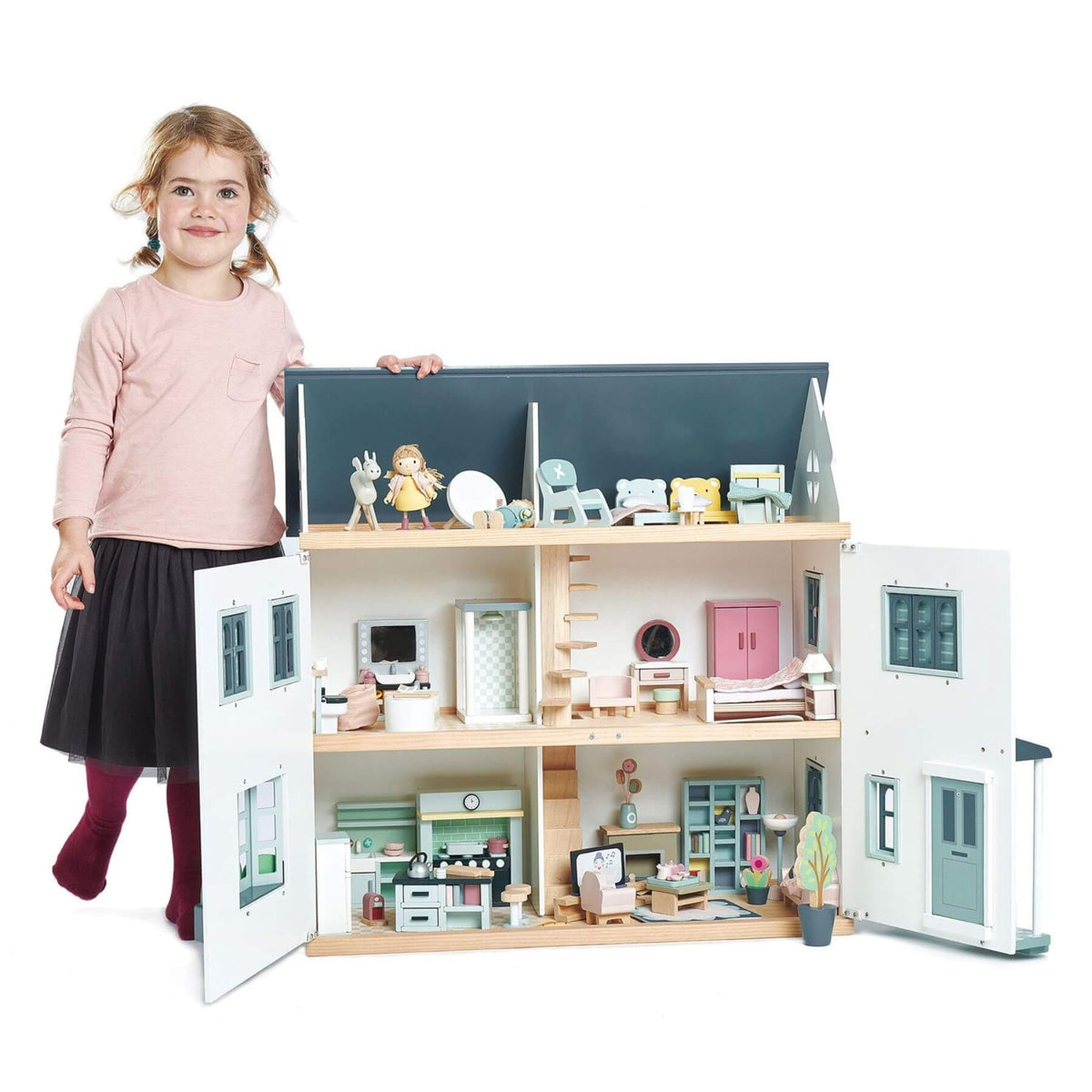 Child with a large dollhouse featuring various rooms and furniture.