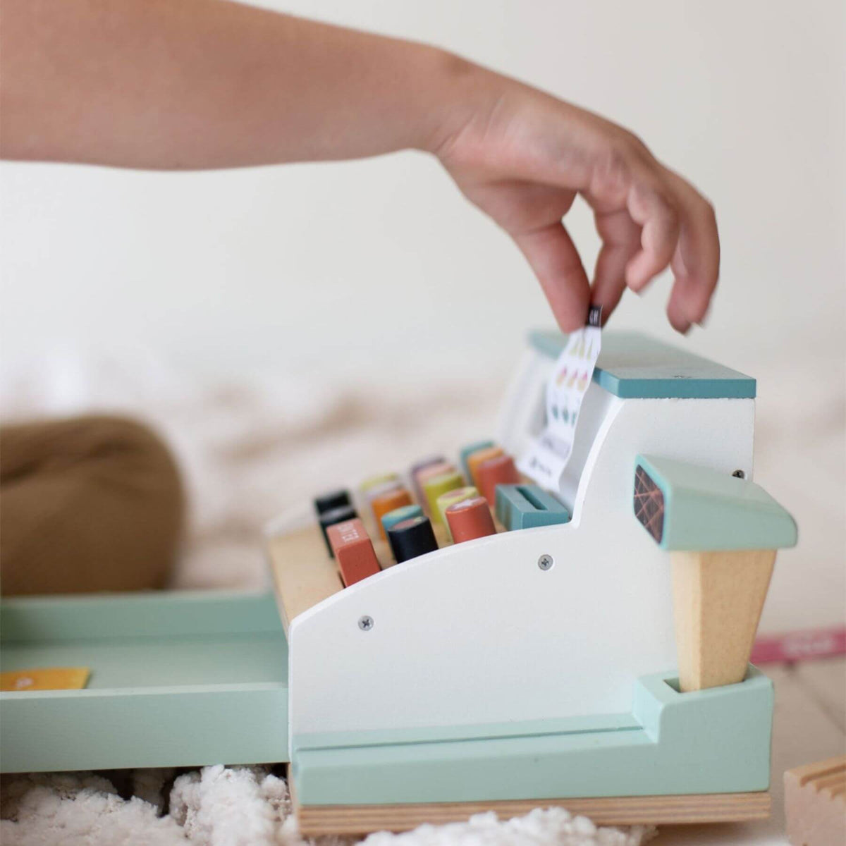 Wooden toy cash register with colorful buttons on a soft surface