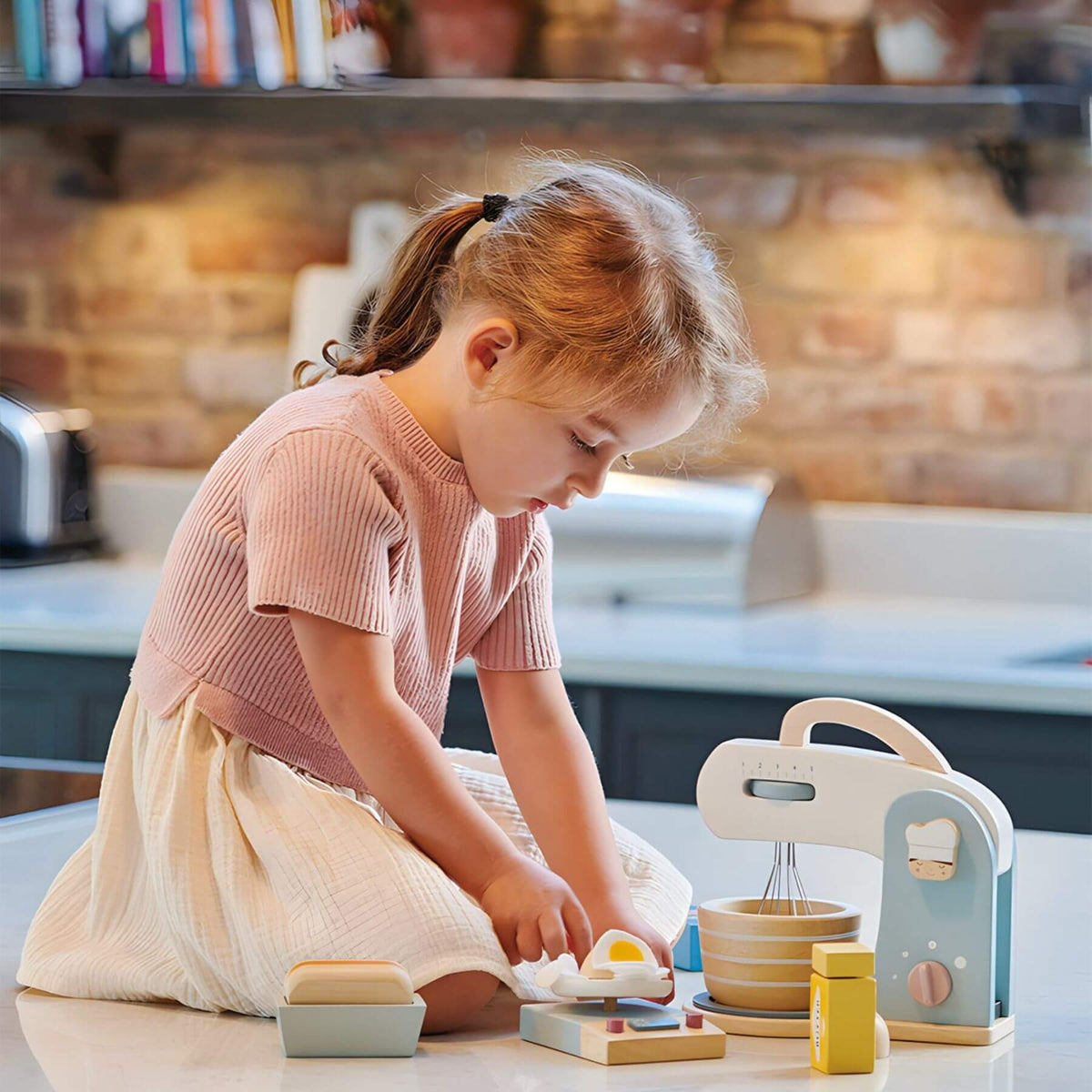 Child playing with a toy kitchen set in a kitchen