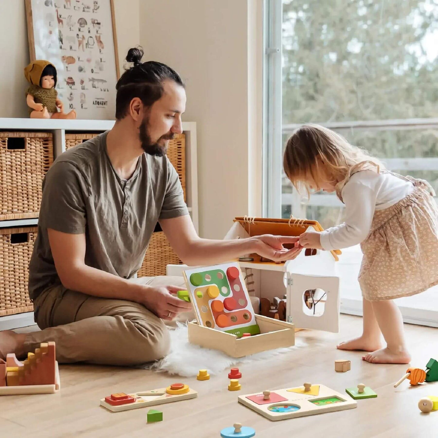 Man and child playing with educational toys on a wooden floor.