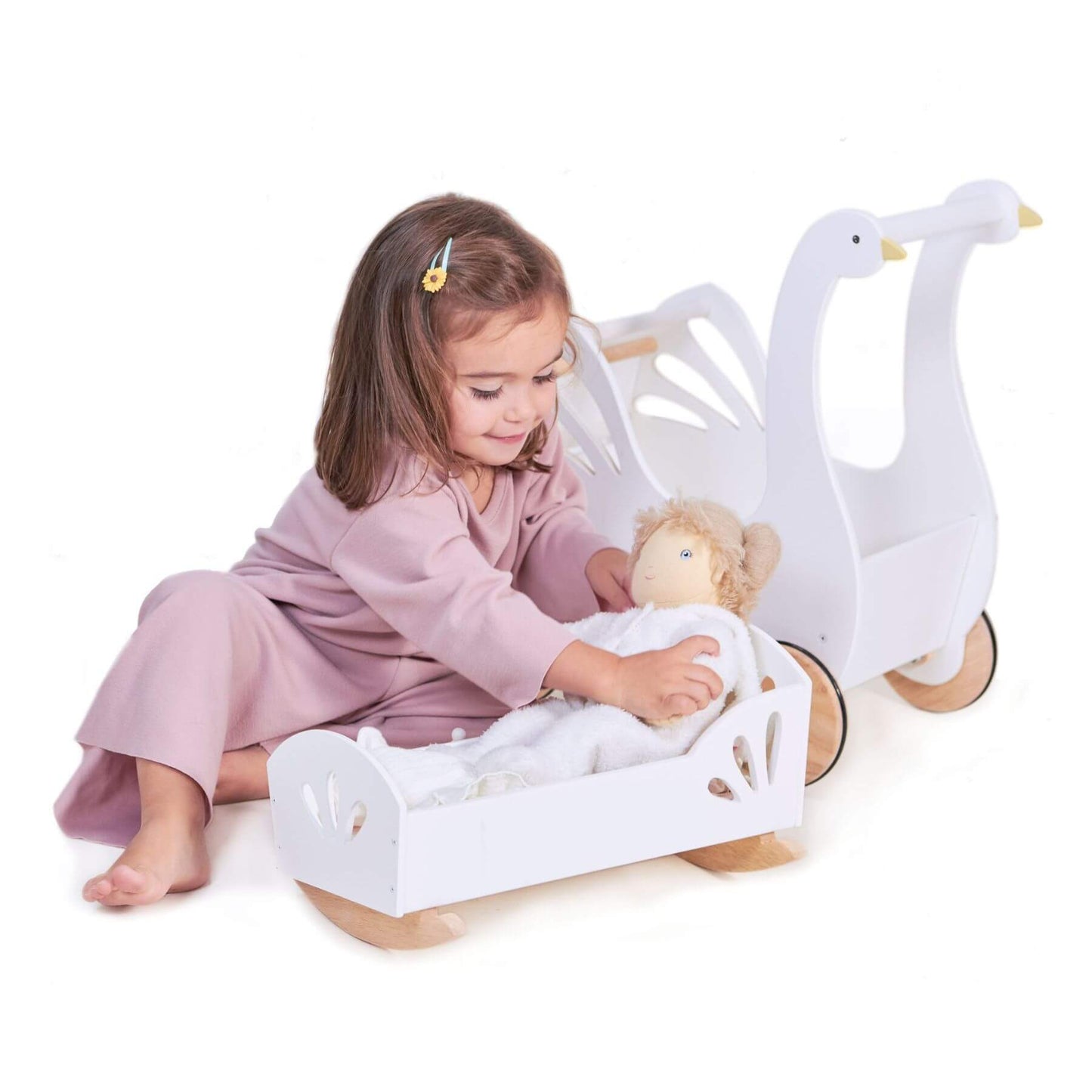 Child playing with a toy swan and baby crib on a white background