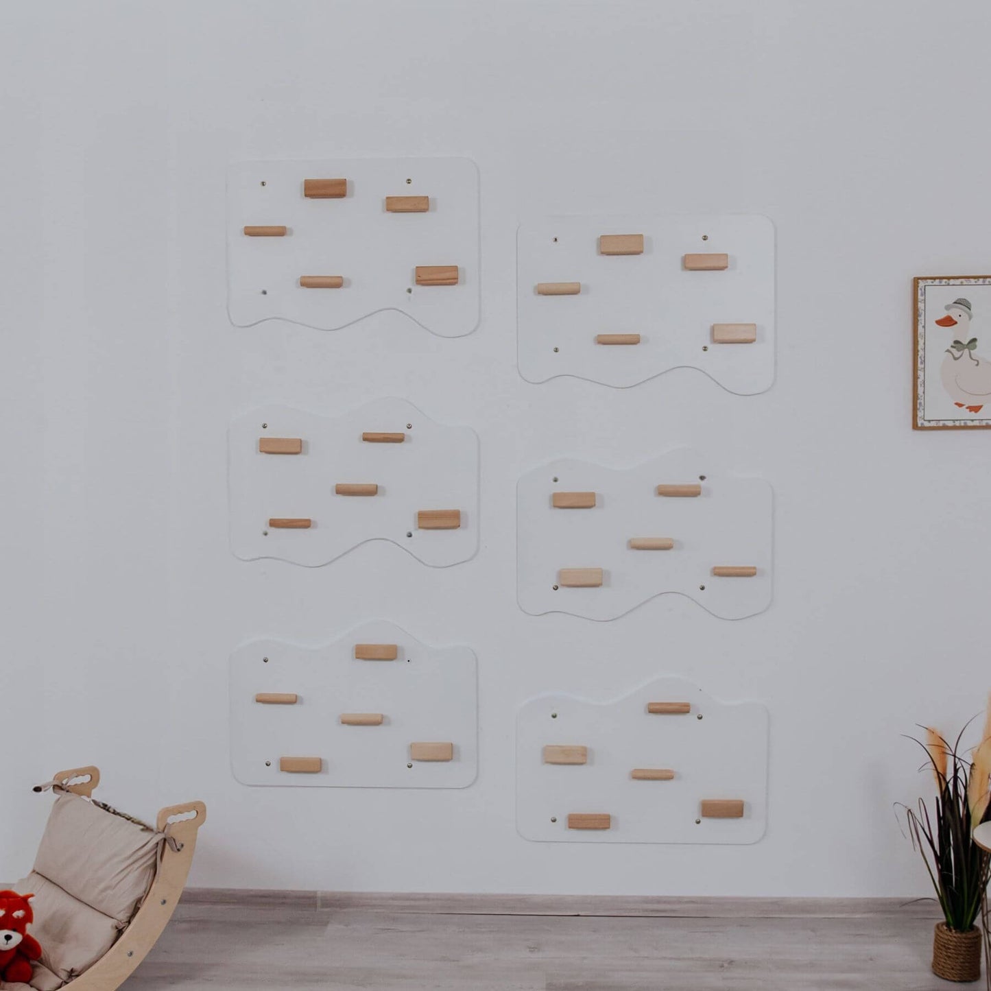 Wooden climbing wall panels on a white wall with a wooden rocking chair and plant in the foreground.