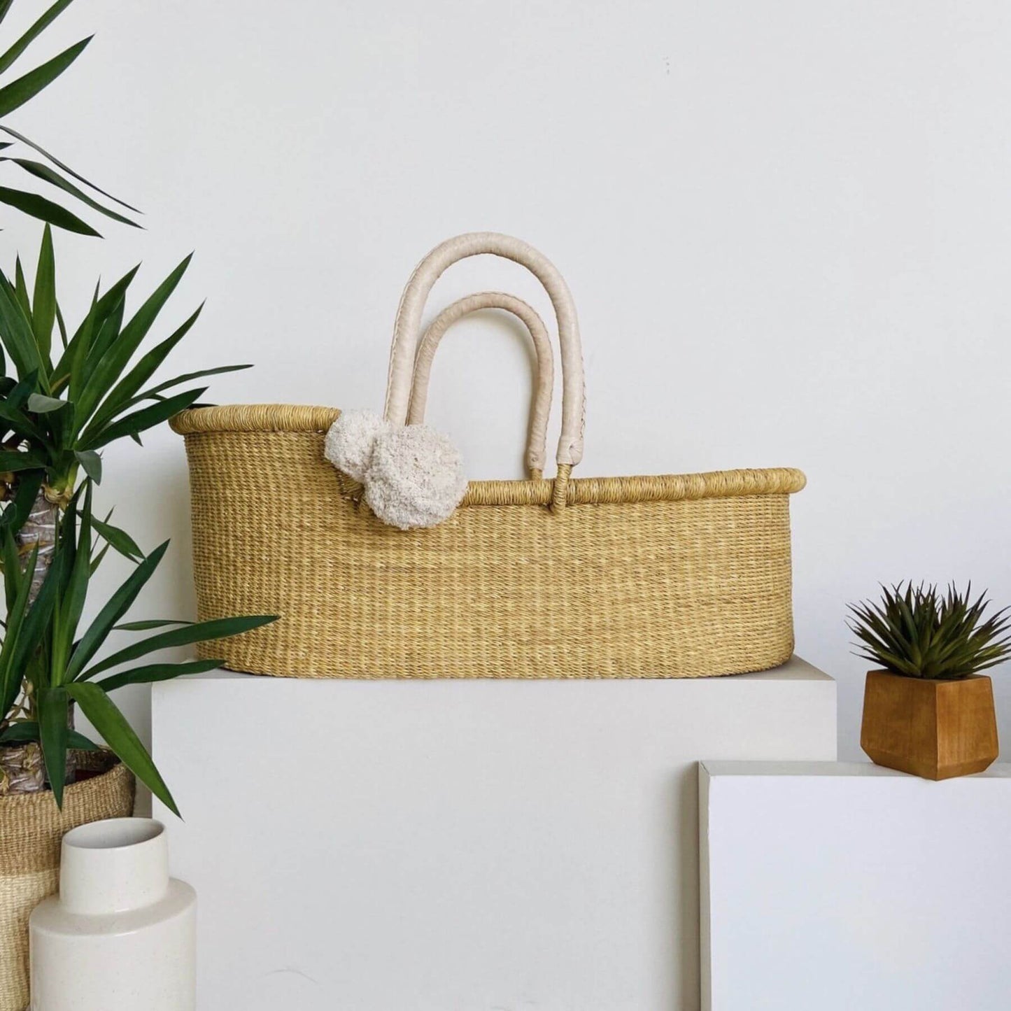 Plum+Sparrow African Moses Basket Cream Handle on a white surface with plants and decor items.