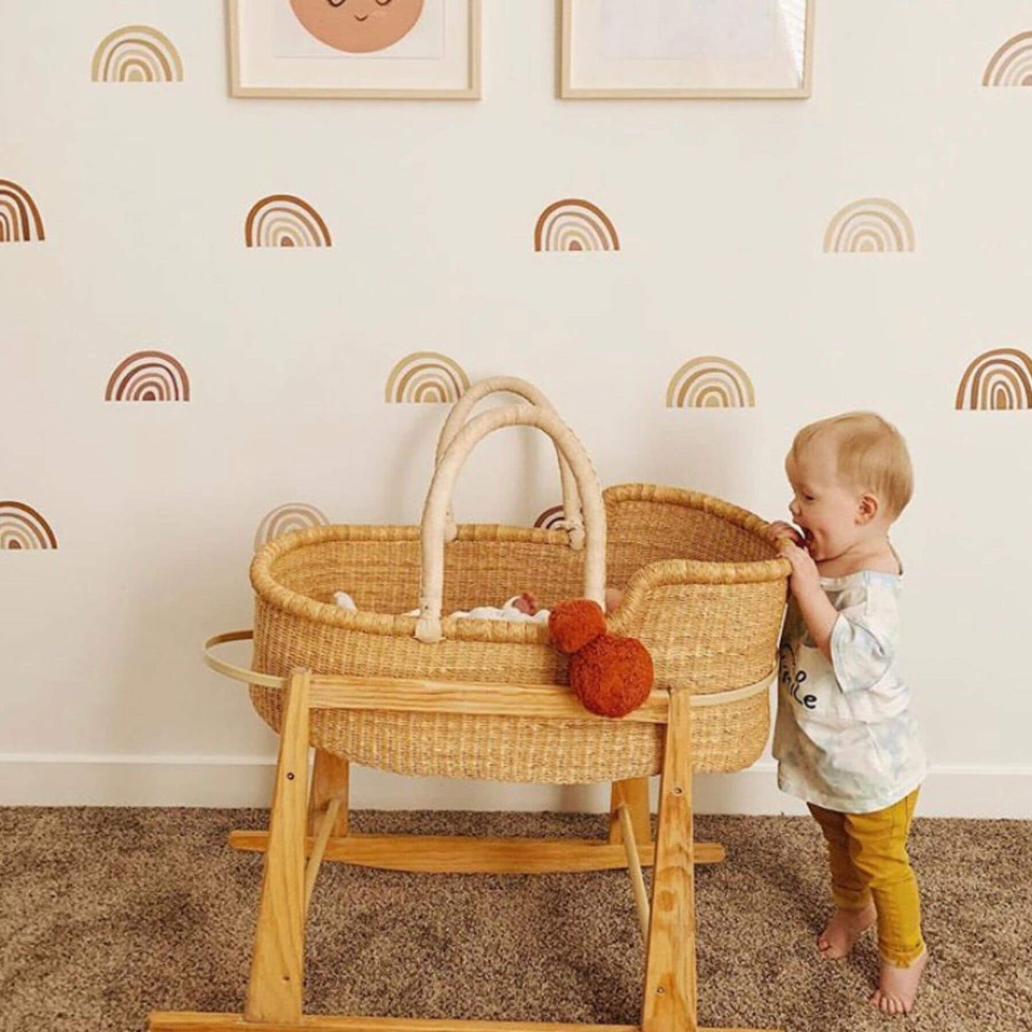 Child playing with Plum+Sparrow African Moses Basket Cream Handle in a room with rainbow wall decals.