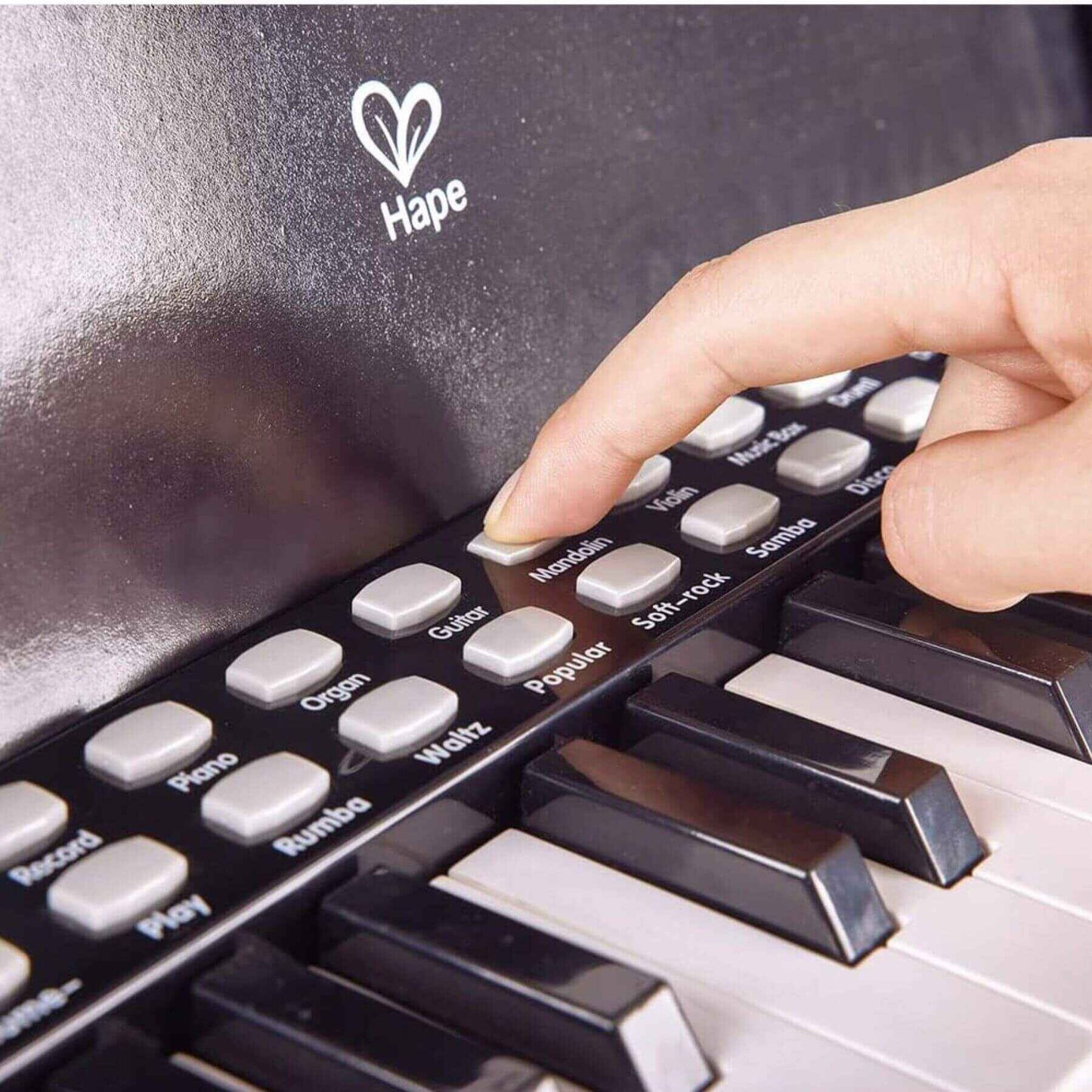 Hand pressing a button on a Hape toy piano