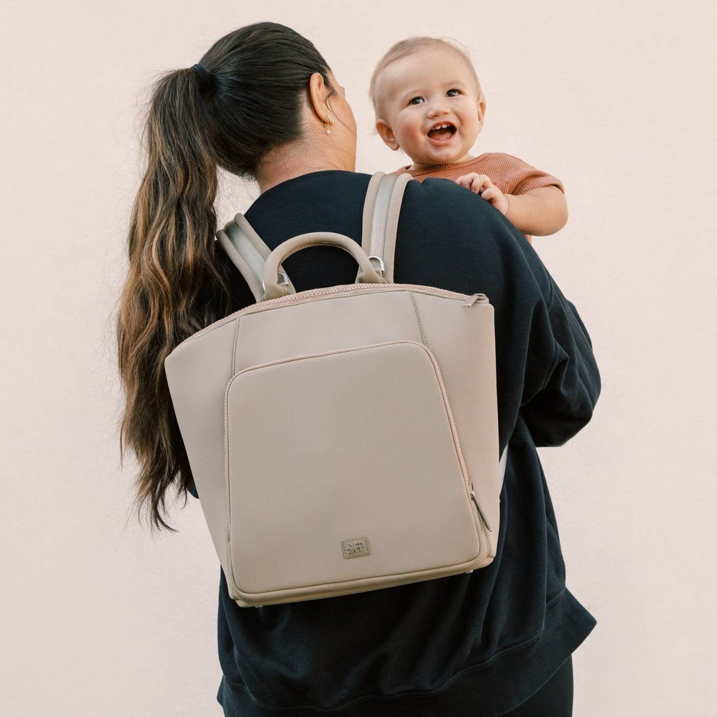 Woman carrying a baby and Freshly Picked Aspen Seoul Neoprene Backpack II