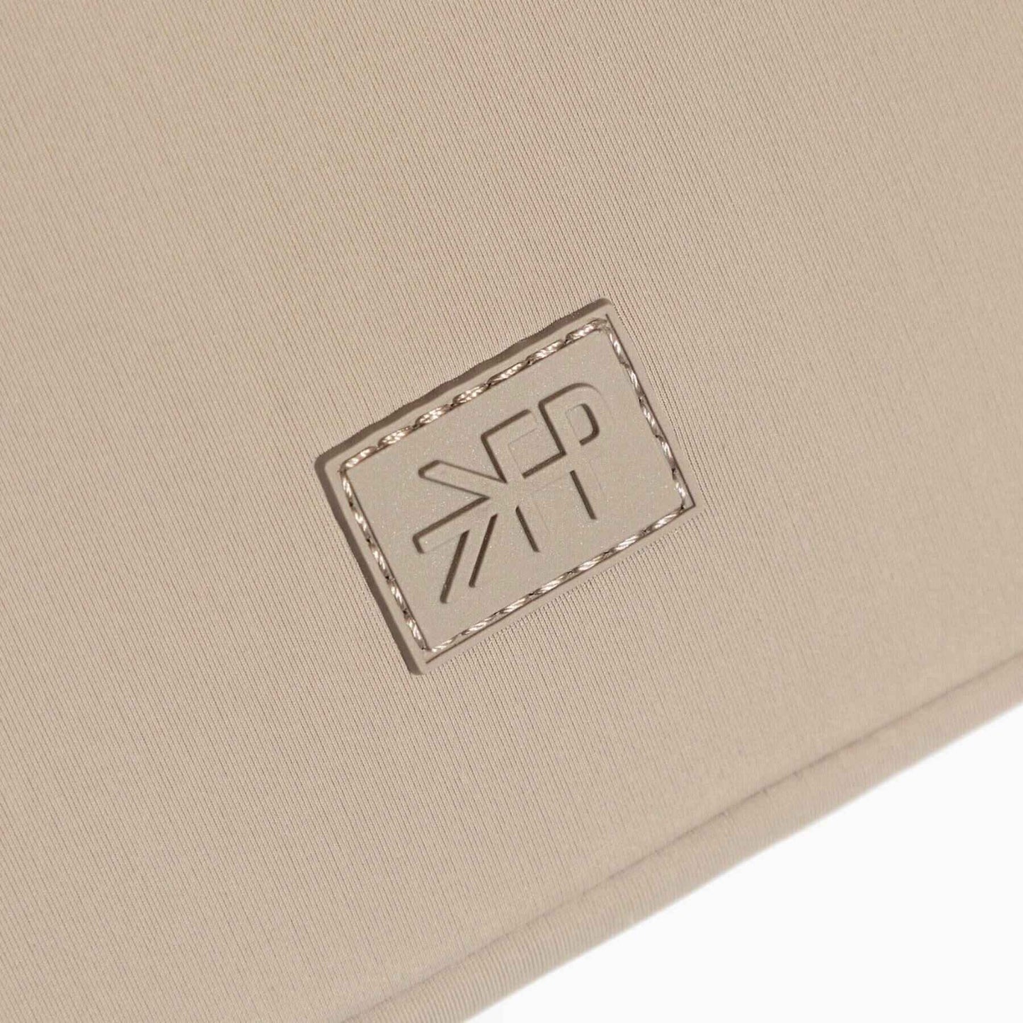 Close-up of a beige fabric surface with a logo patch.