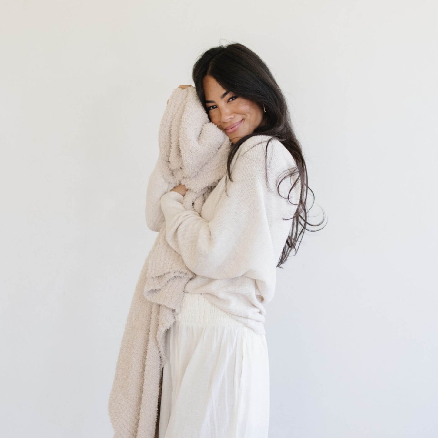 Woman holding Saranoni Bamboni® Throw Blanket in a white robe against a plain background