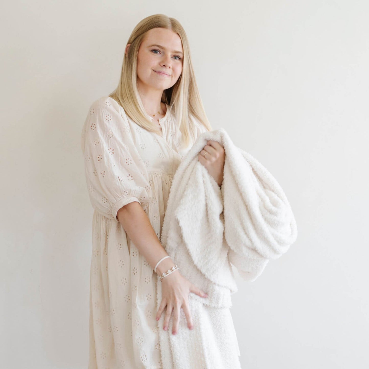 Woman wearing a white dress with Saranoni Bamboni® Throw Blanket overlay against a plain background