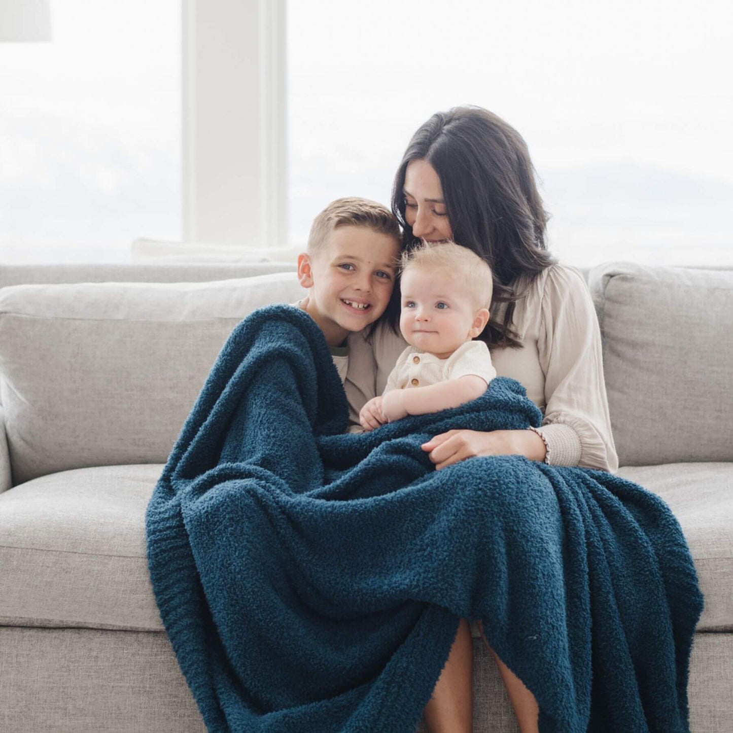 Woman and two children sitting on a couch with Saranoni Bamboni® Throw Blanket