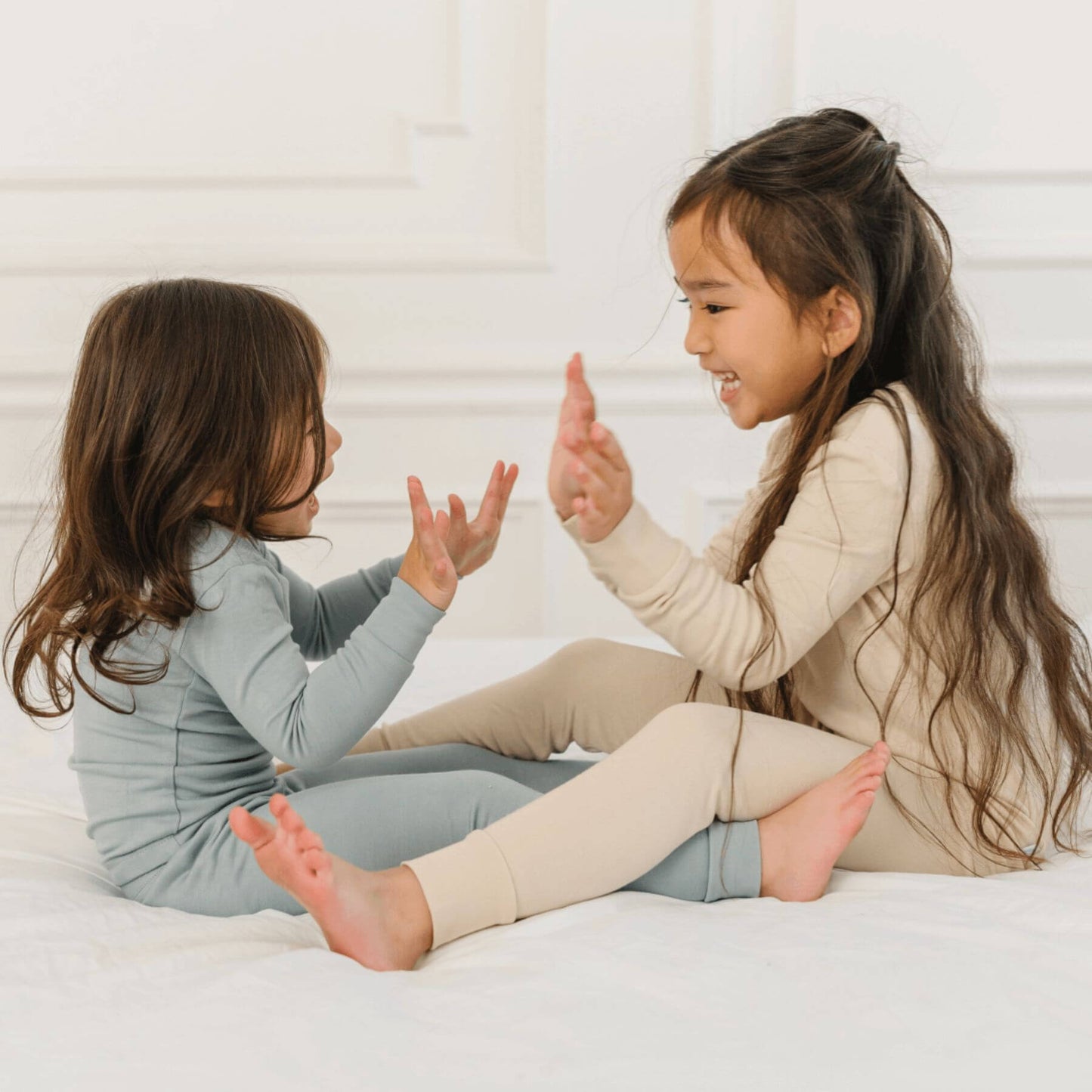 Two girls in Dreamland Baby Toddler/Kids Bamboo Pajamas, sitting on bed