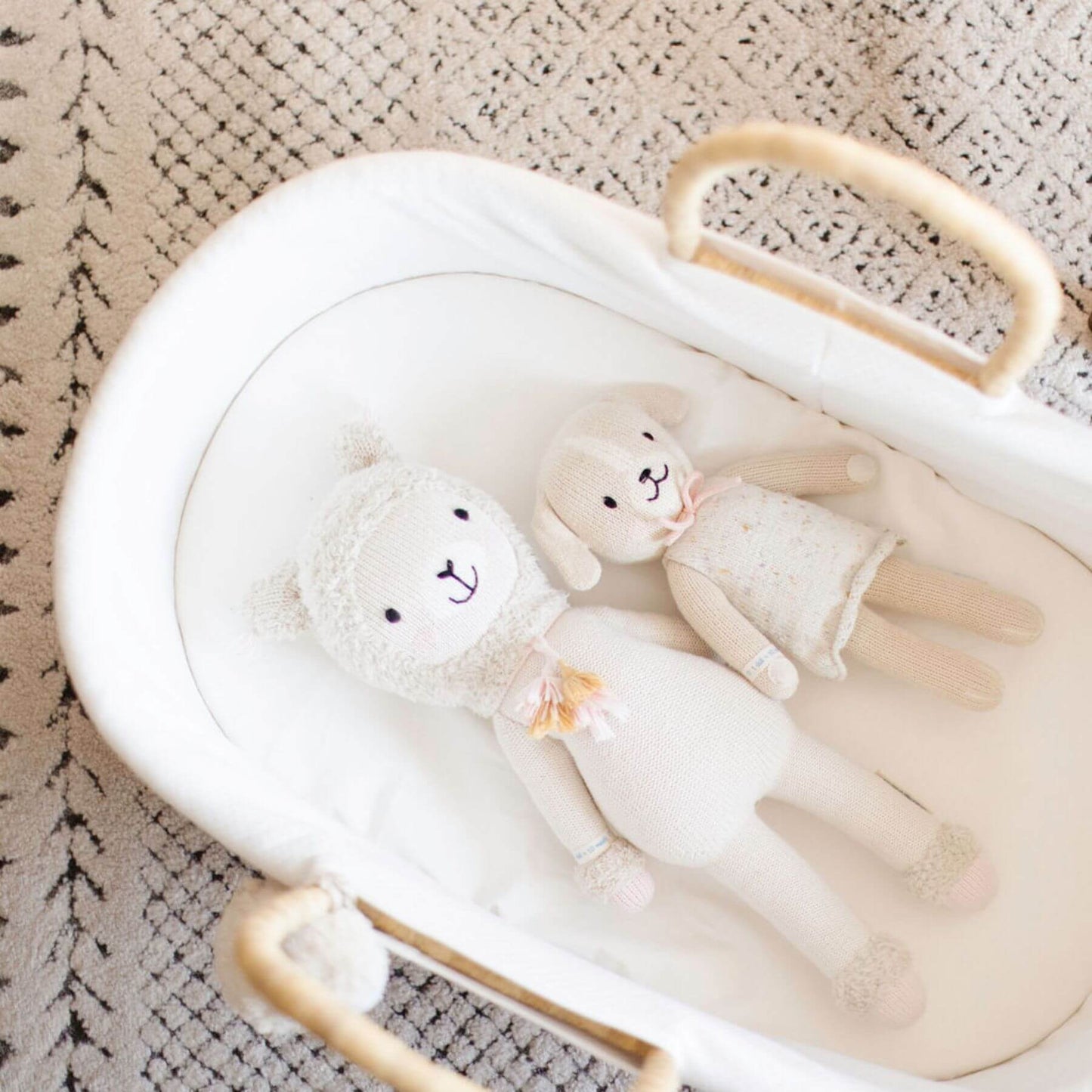 White baby crib with two plush toys on a textured surface