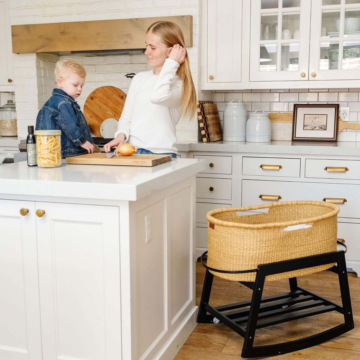 Woman and child in a kitchen with African Moses Basket No Hood Inset Handle on the floor.