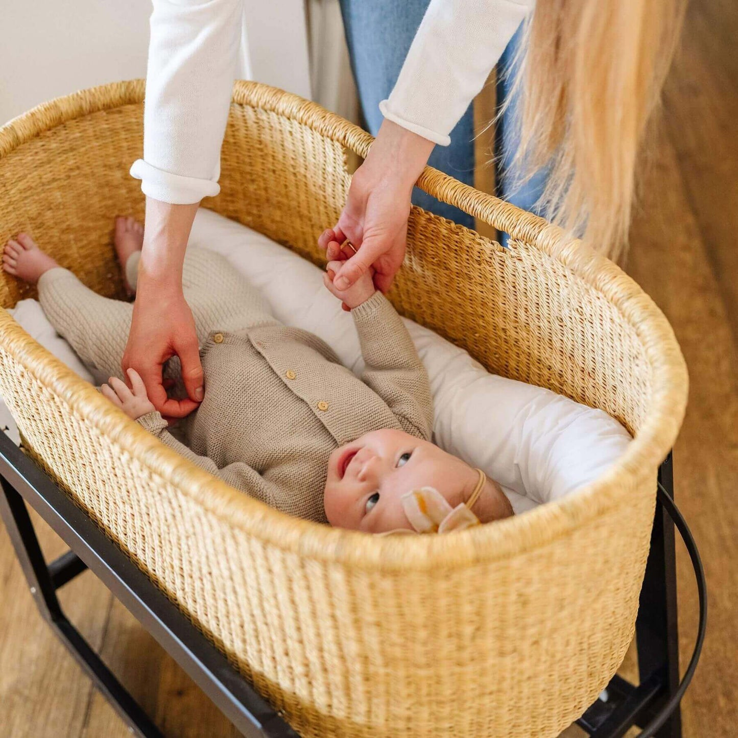 Baby in African Moses Basket No Hood Inset Handle with a person adjusting the blanket