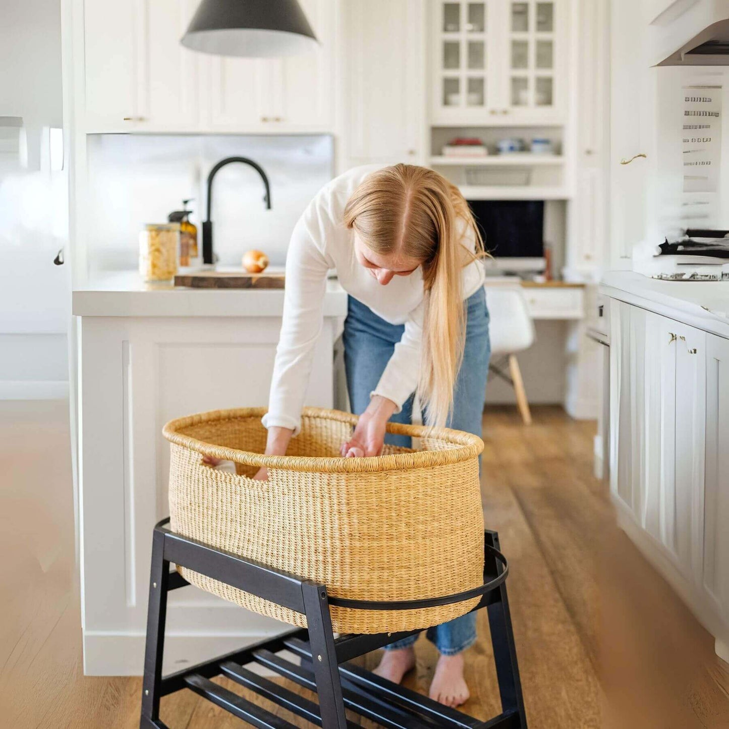 Woman arranging African Moses Basket No Hood Inset Handle on a stand in a kitchen.