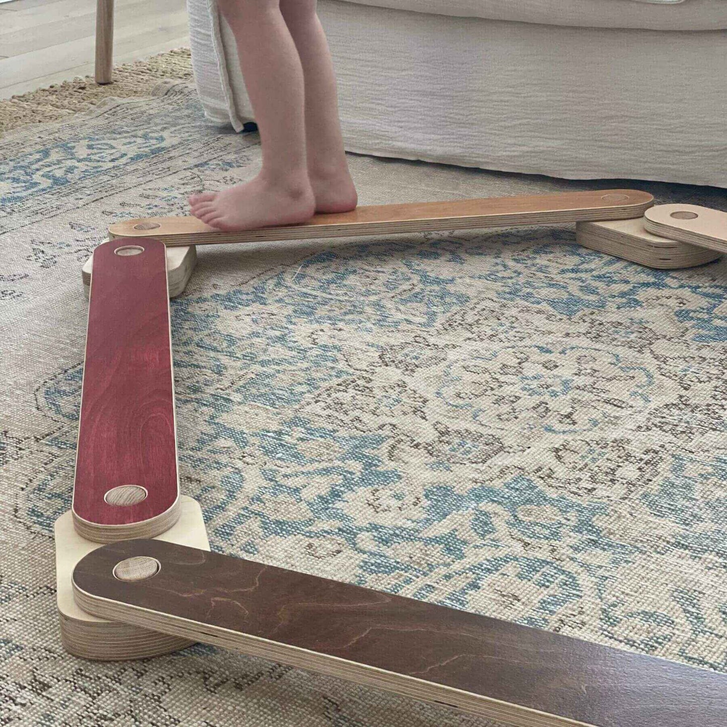Child standing on a balance board on a patterned rug