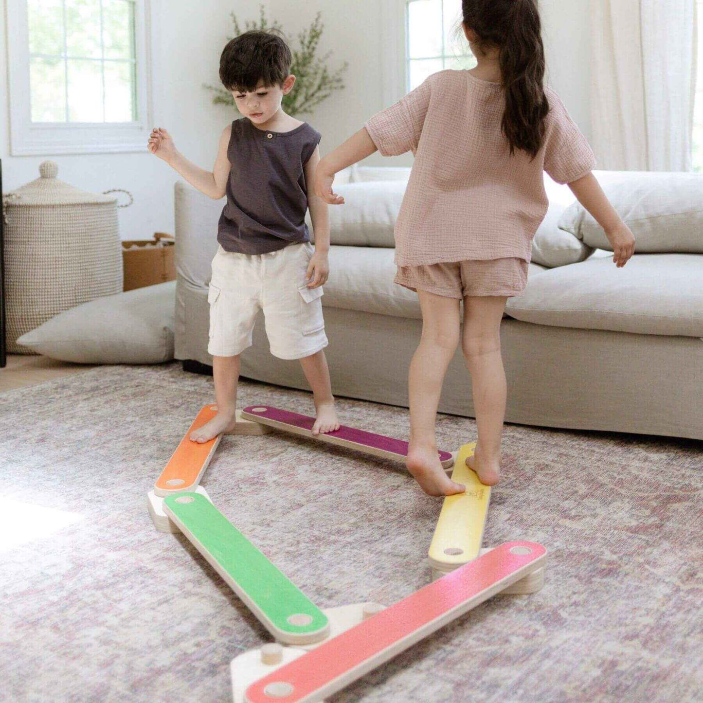 Two children playing with Bunny Hopkins Balance Beam in a living room.