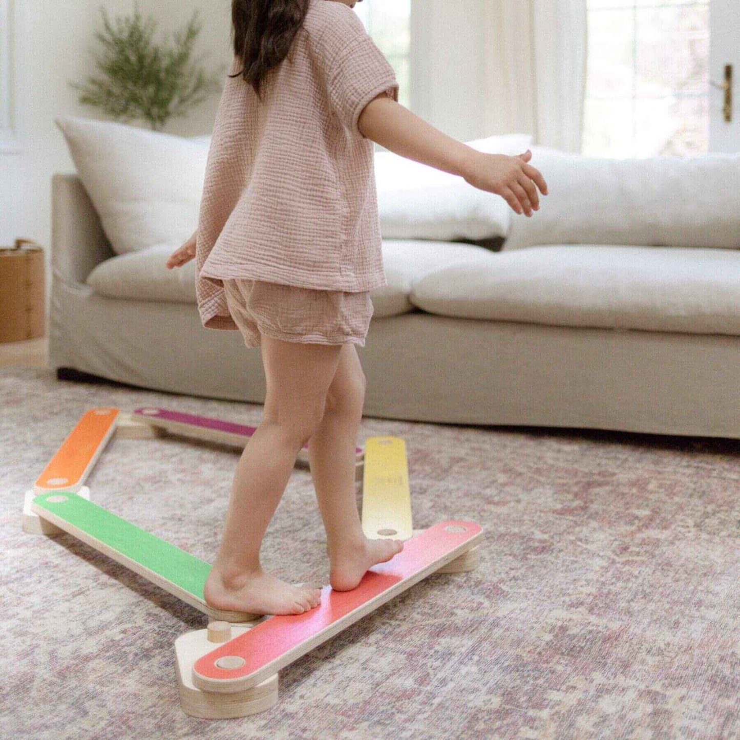 Child standing on Bunny Hopkins Balance Beam in a living room.
