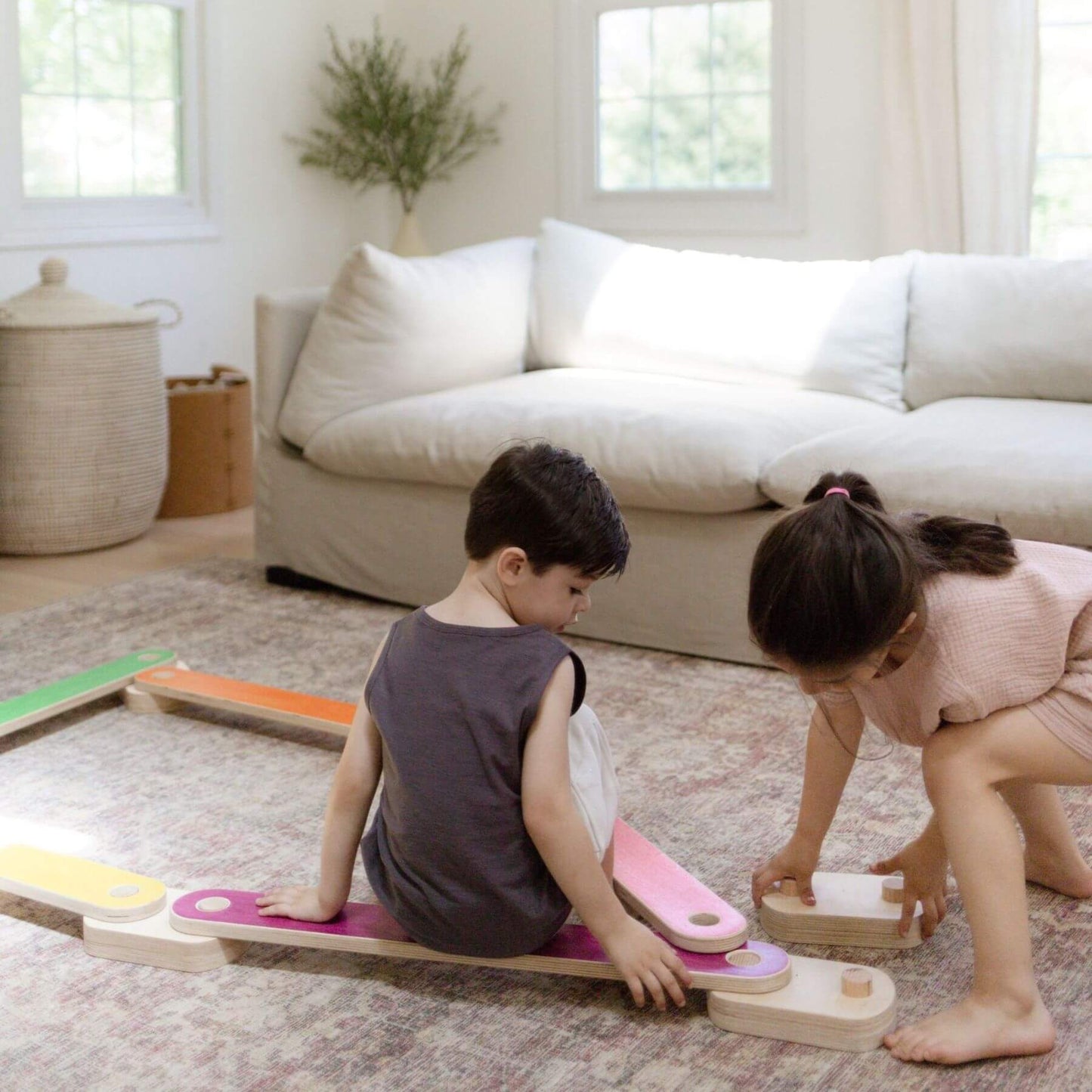 Two children playing with Bunny Hopkins Balance Beam in a living room.