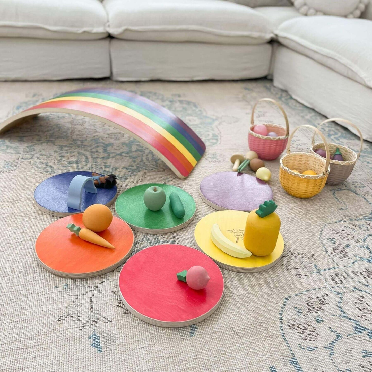 Colorful wooden toys on a rug with a rainbow and baskets in the background