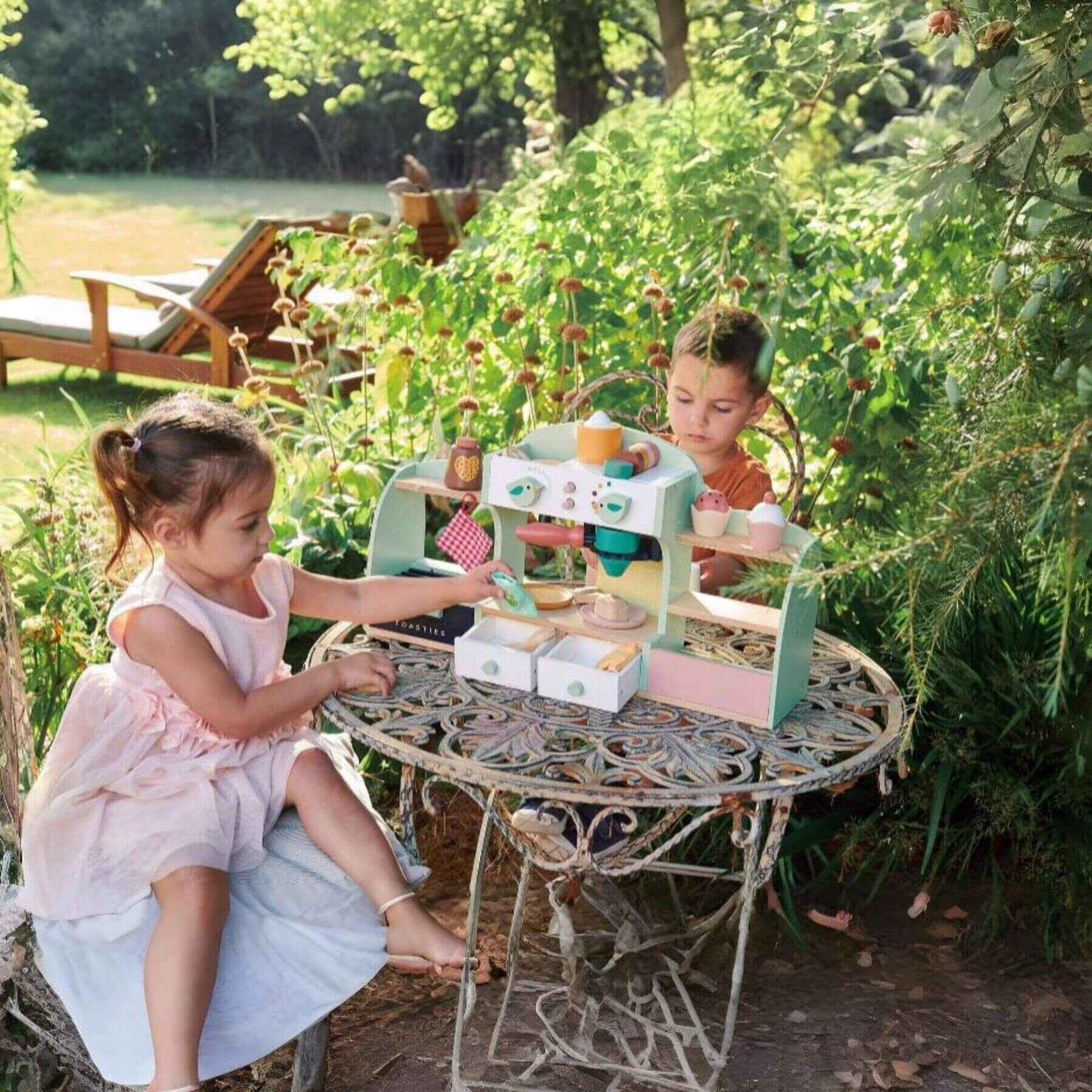 Two children playing with Tender Leaf Bird’s Nest Café outdoors in a garden.