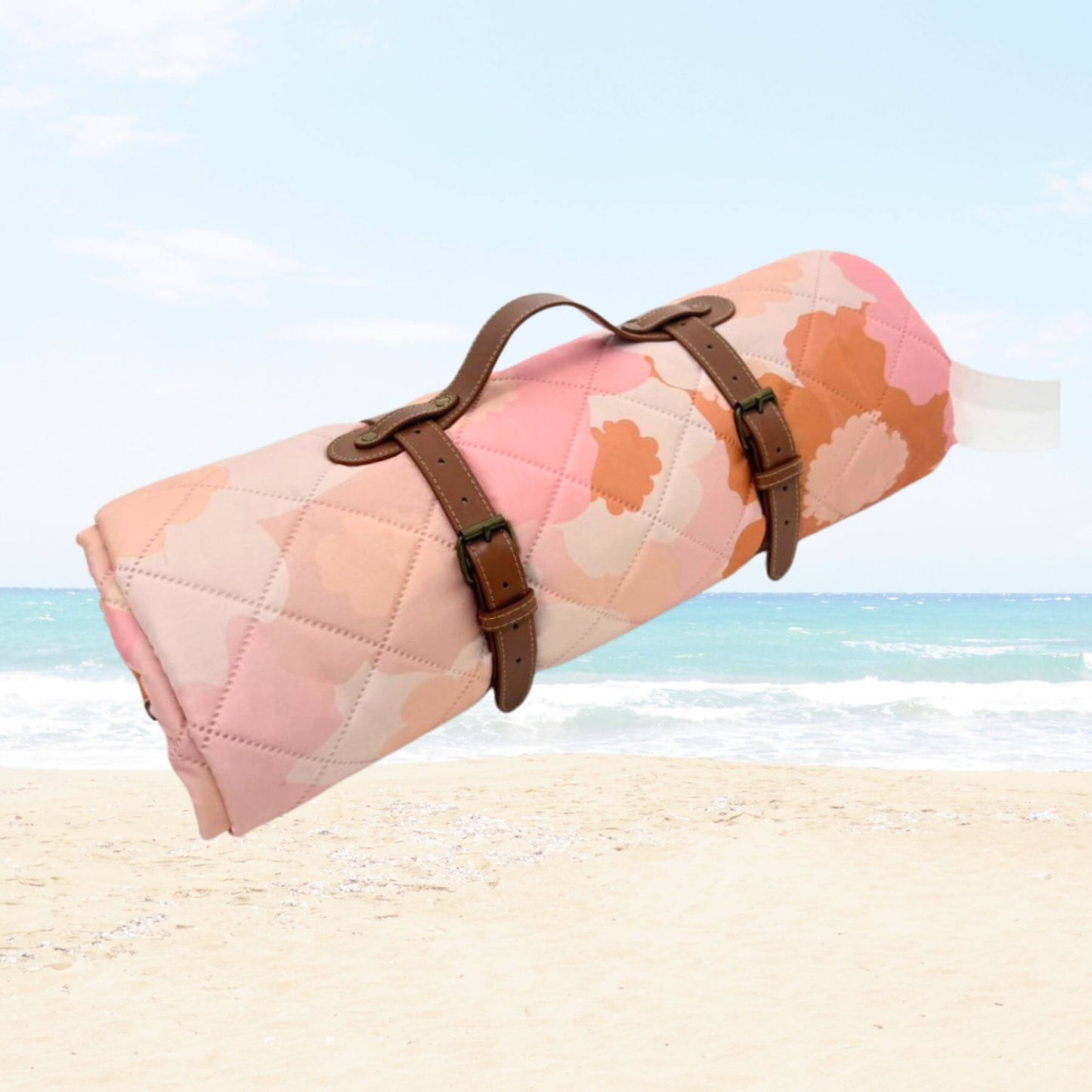 Blush Meadow Quilted Water Resistant Beach Mat with brown straps on a beach