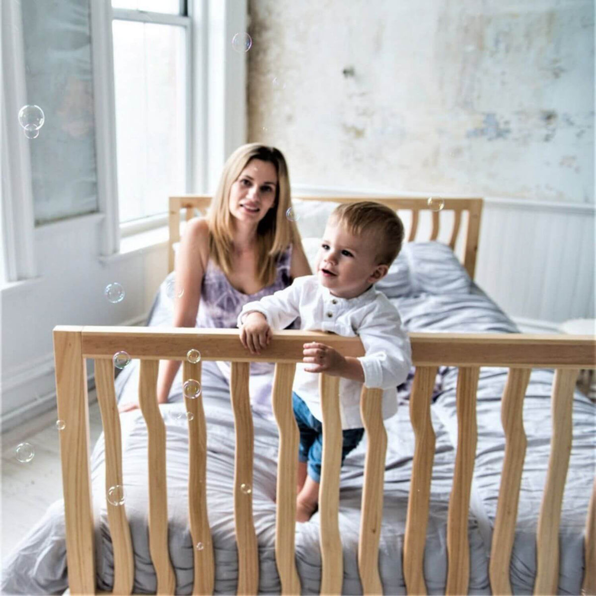Woman and child on a bed with bubbles in a bright room