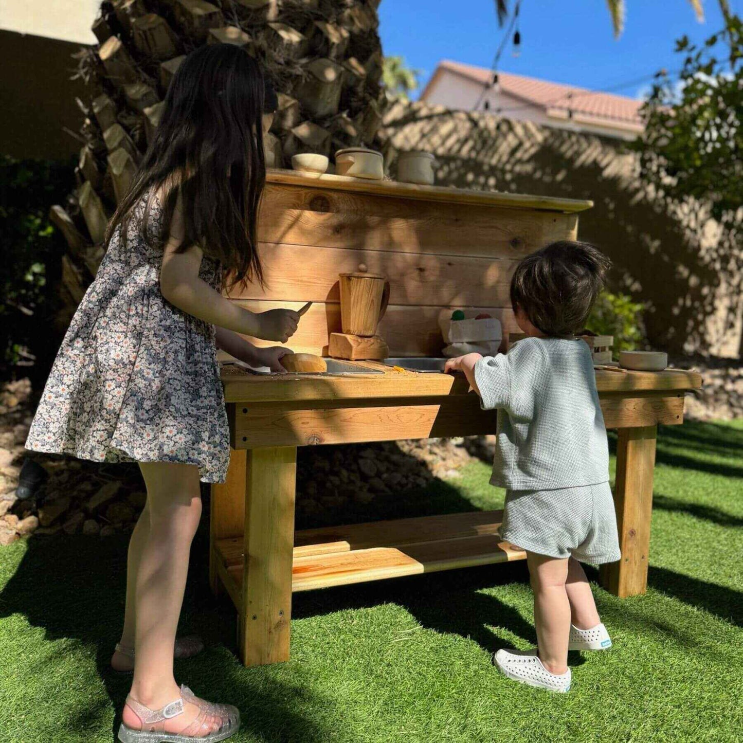 Two children playing at Bunny Hopkins Mud Kitchen with pots and pans.