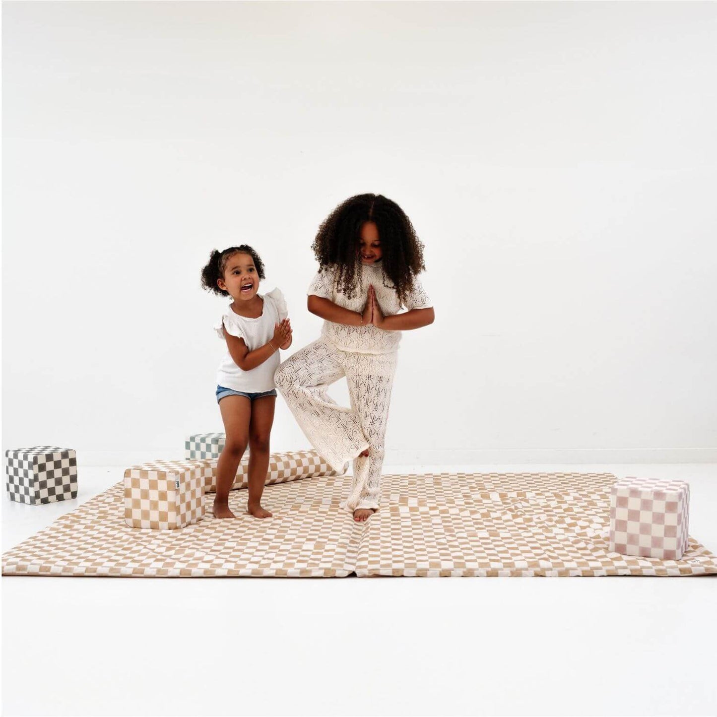 Two people practicing yoga on Toki Kids Checker Toffee Organic Cotton Mat