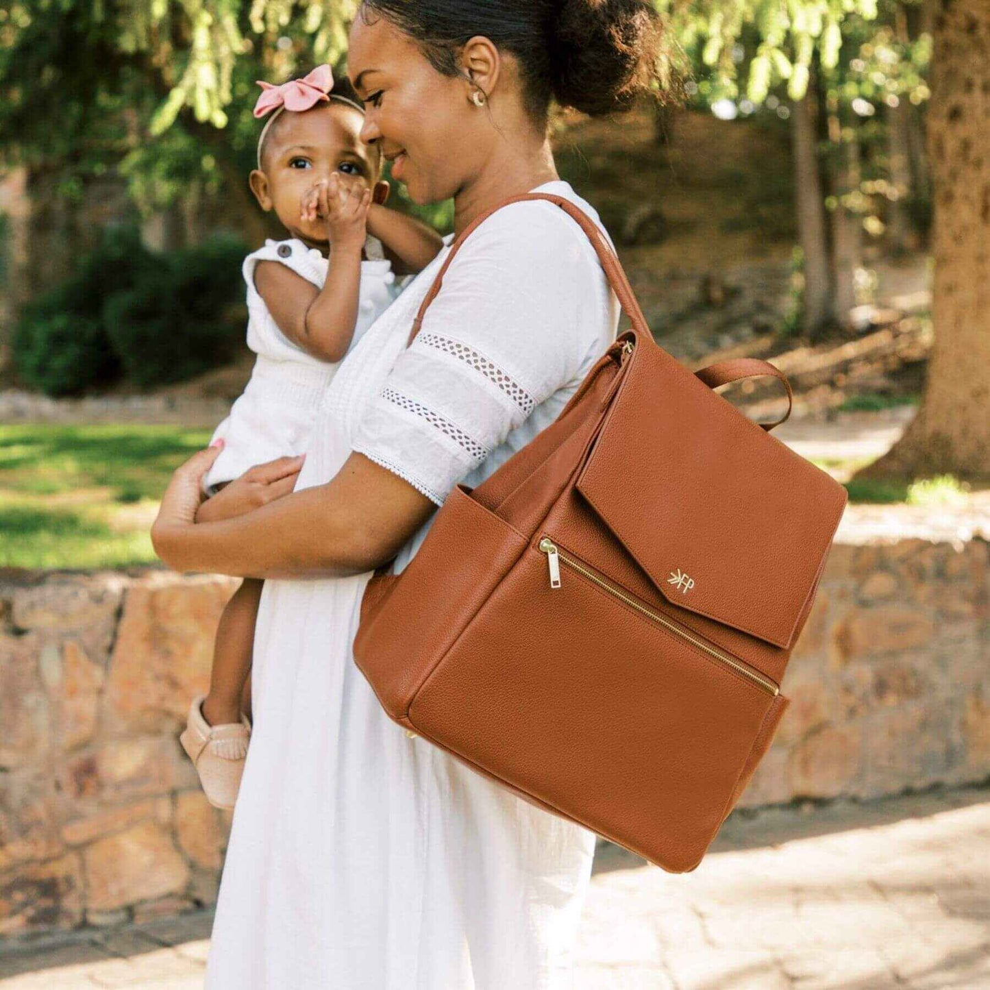 Woman holding a child and Cognac Classic Diaper Bag II outdoors