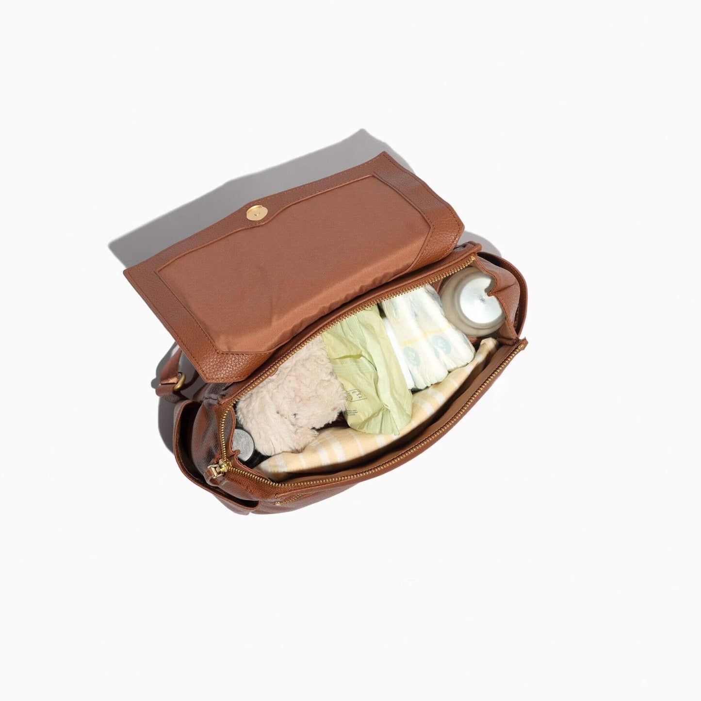 Cognac Mini Classic Bag II with a gray interior, containing baby items on a white background