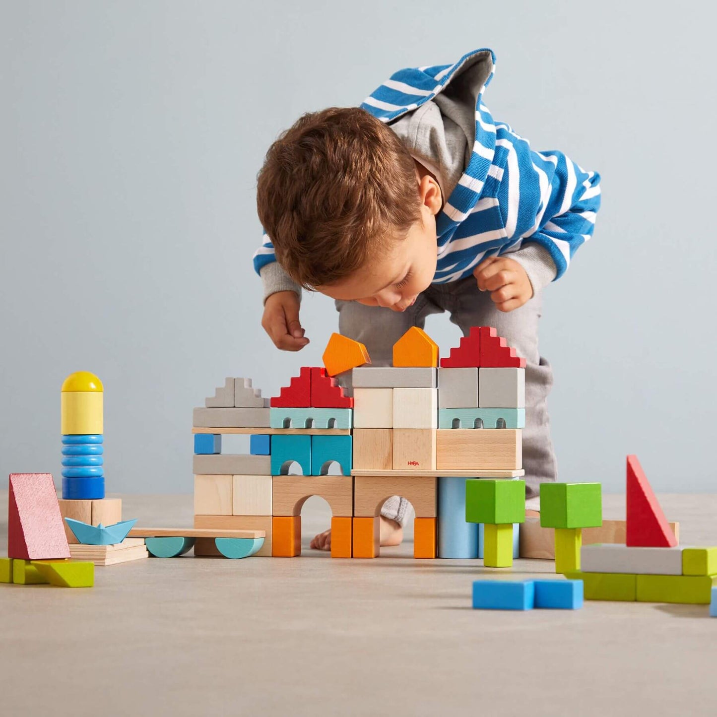 Child playing with HABA USA Colored Wooden Building Blocks - 85 Piece Set