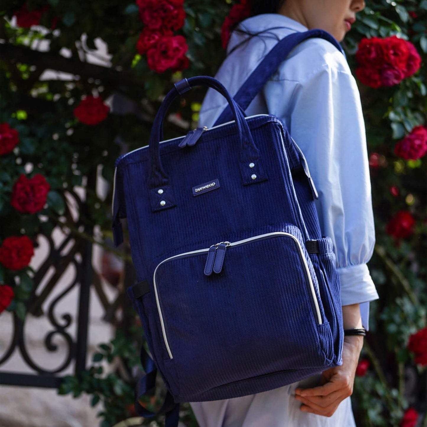 Person wearing Corduroy Diaper Backpack Blue with floral background