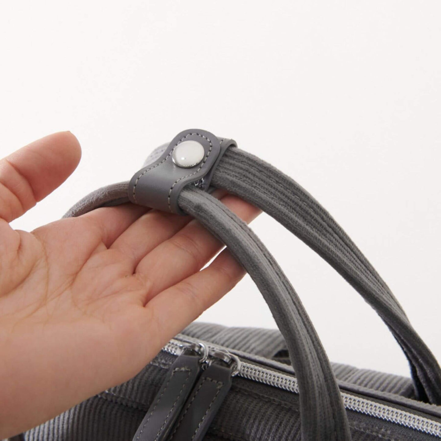 Hand holding a gray strap of Corduroy Diaper Backpack Grey