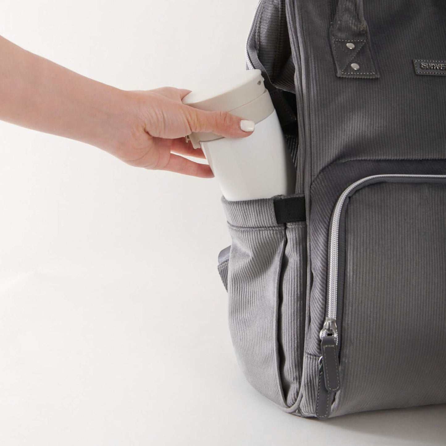 Person placing a white container into Corduroy Diaper Backpack Grey