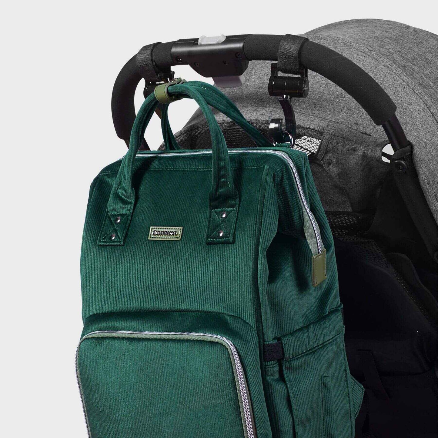 Corduroy Diaper Backpack Green attached to a stroller on a light gray background
