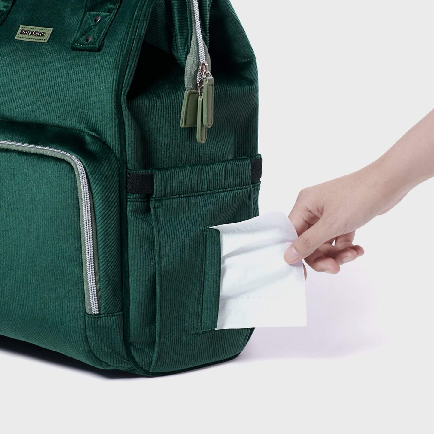Corduroy Diaper Backpack Green with a hand pulling out a white paper from a pocket