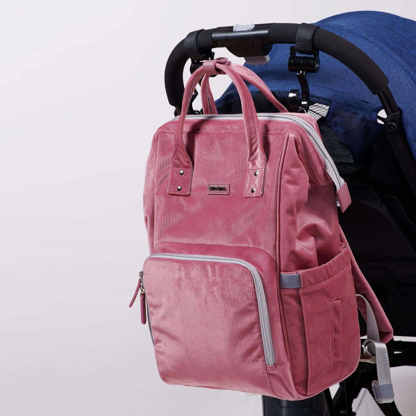 Corduroy Diaper Backpack Pink attached to a stroller on a white background