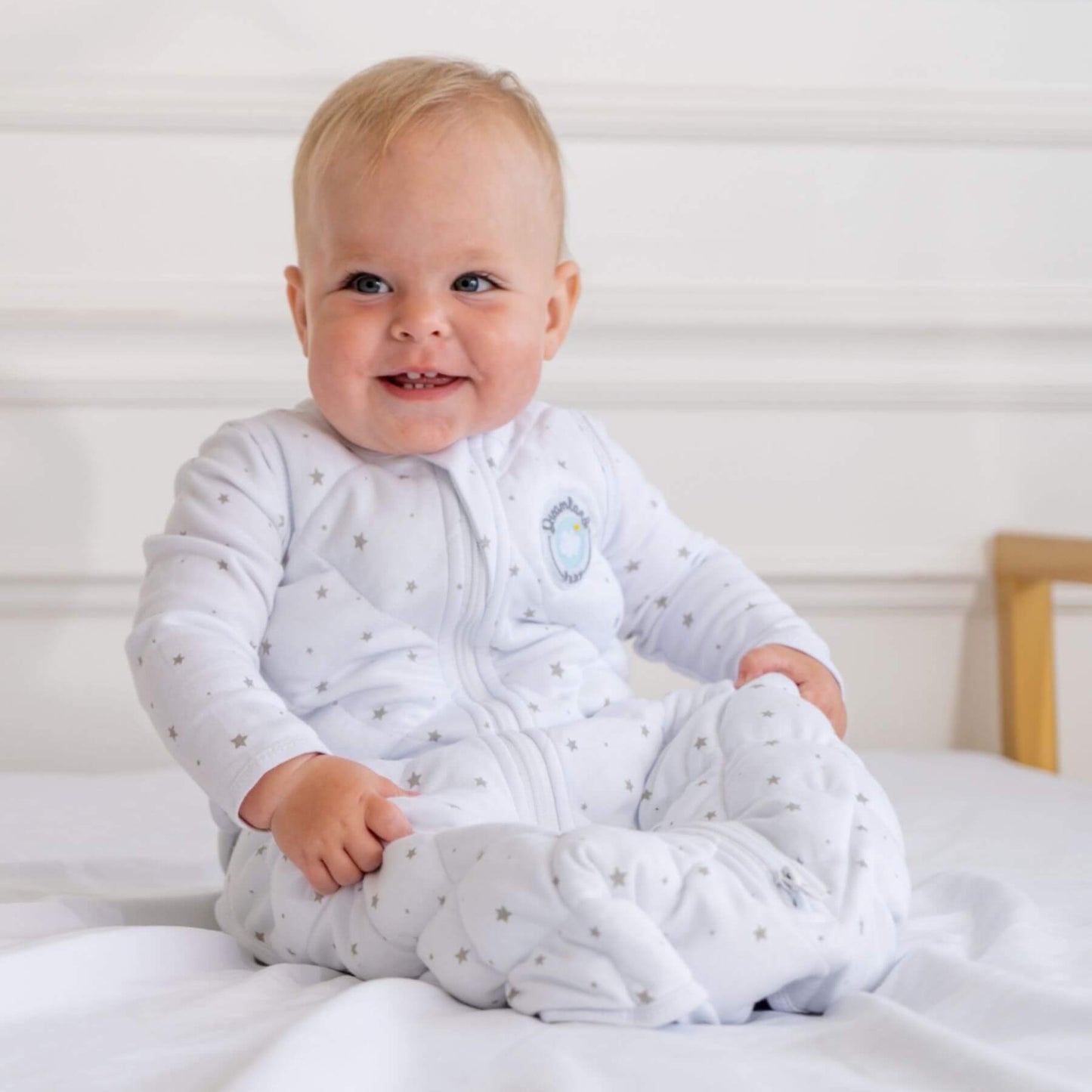 Baby in Dreamland Baby Dream Weighted Sleep Sack Grey Star sitting on a bed.
