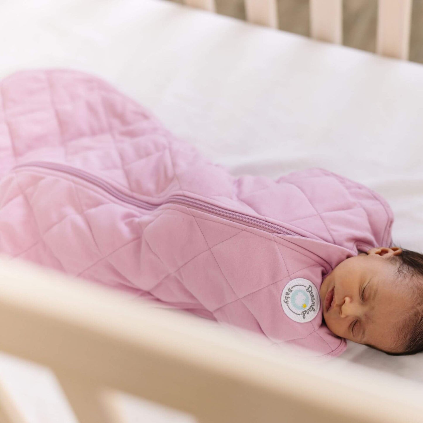 Baby sleeping in Dream Weighted Sleep Swaddle - Mauve in a crib.