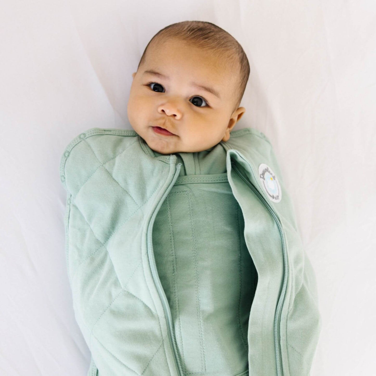 Baby wearing Dream Weighted Sleep Swaddle - Sage on a white background