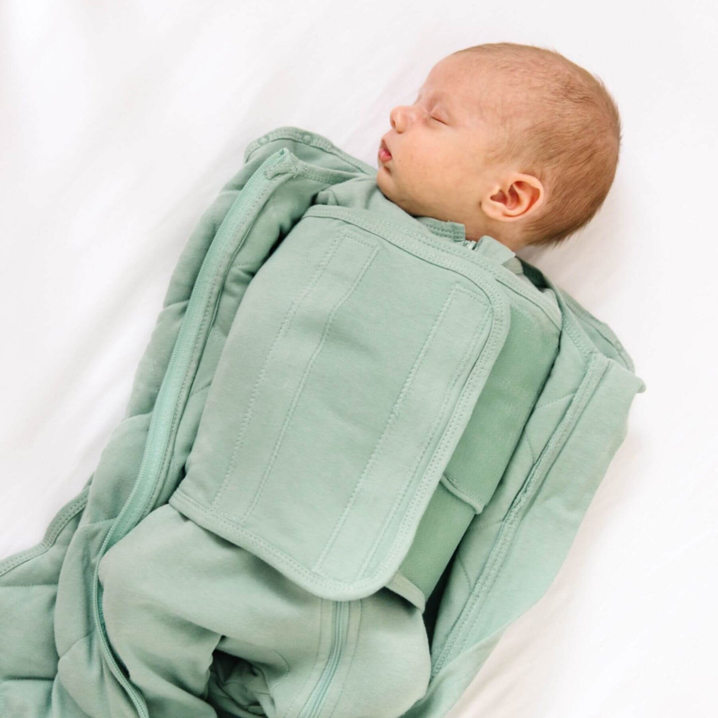 Newborn baby wrapped in Dream Weighted Sleep Swaddle - Sage on a white background