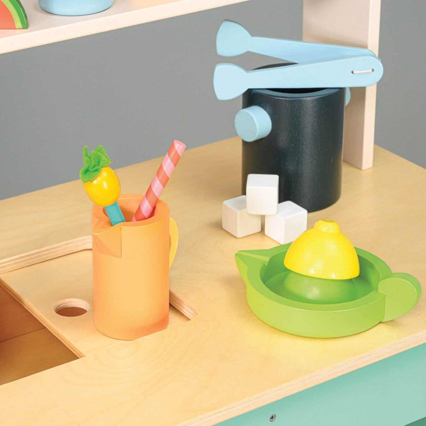 Colorful toy kitchen set on a wooden surface with sink and various utensils.