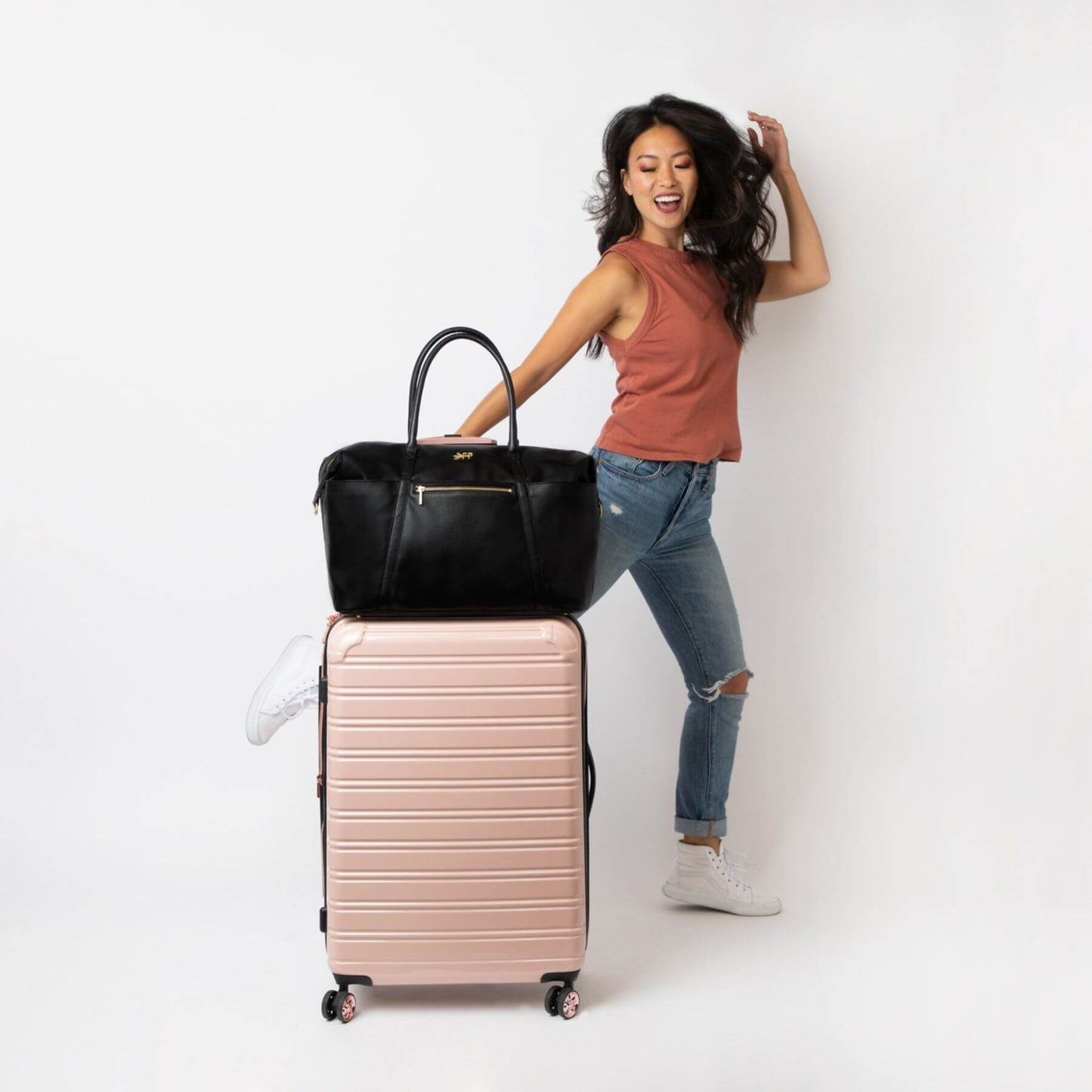 Woman with Ebony Classic Weekender and pink suitcase on a white background