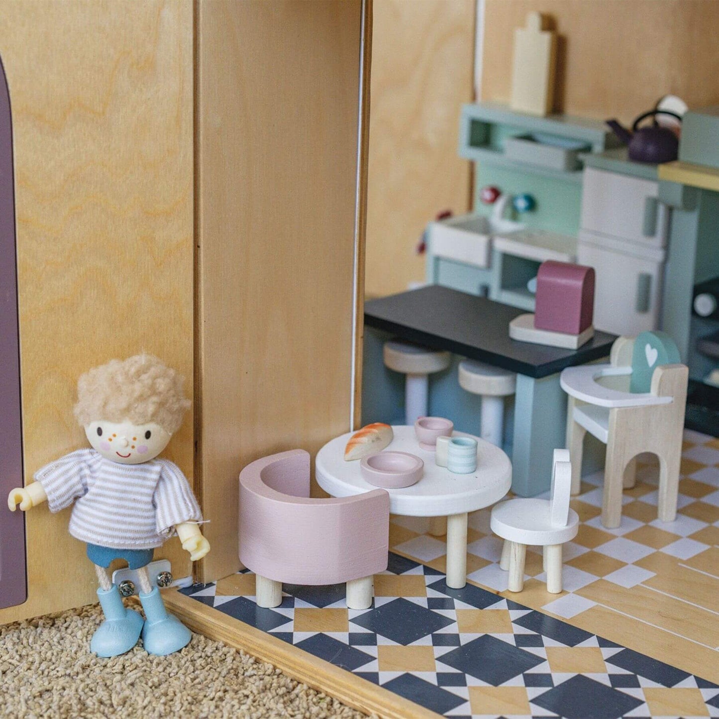 Toy kitchen set with doll and furniture on a checkered floor